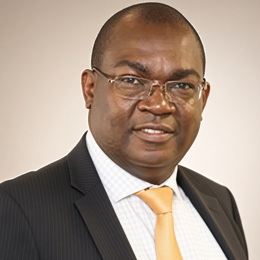 Portrait of a smiling Black man in a dark pinstripe suit, white-checkered shirt, and orange tie, wearing glasses against a neutral backdrop.