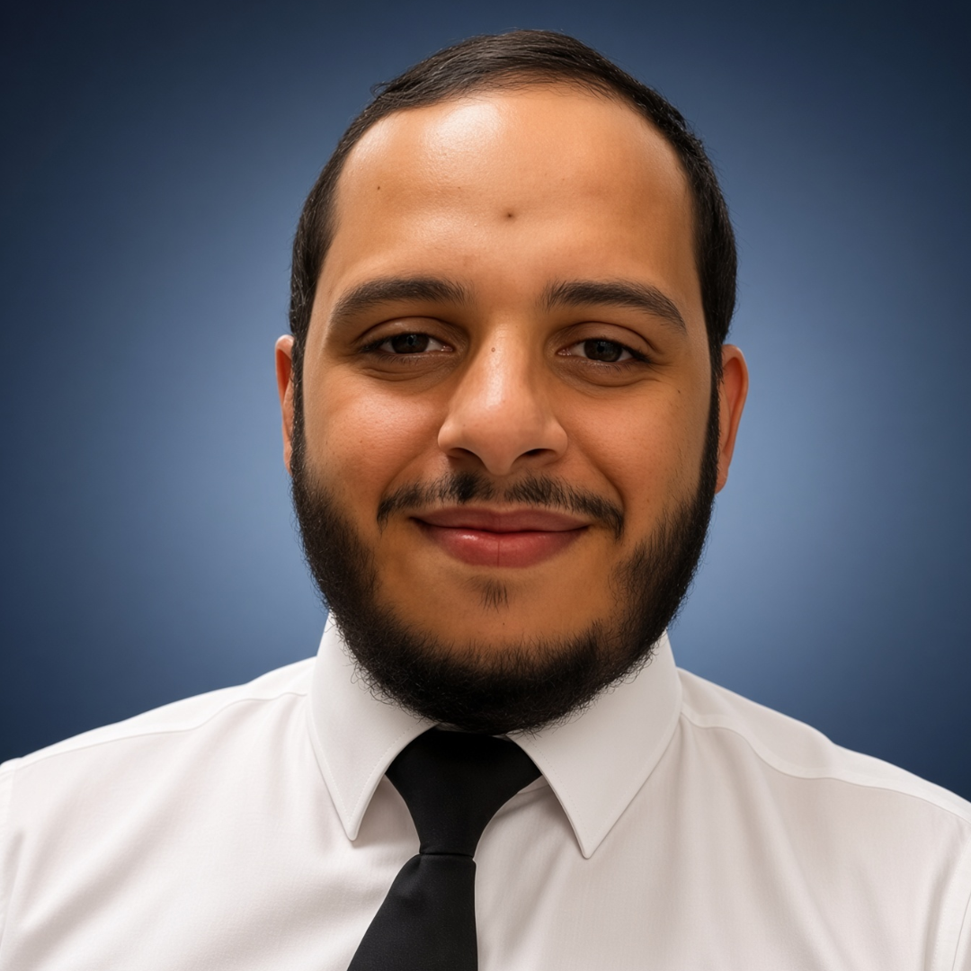 Head-and-shoulders portrait of a smiling man with a beard, wearing a white shirt and black tie against a blue gradient background.