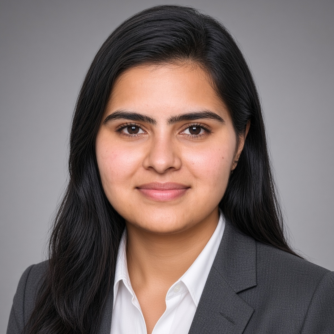 Professional headshot of a woman with long dark hair wearing a gray blazer and white shirt, looking at the camera.